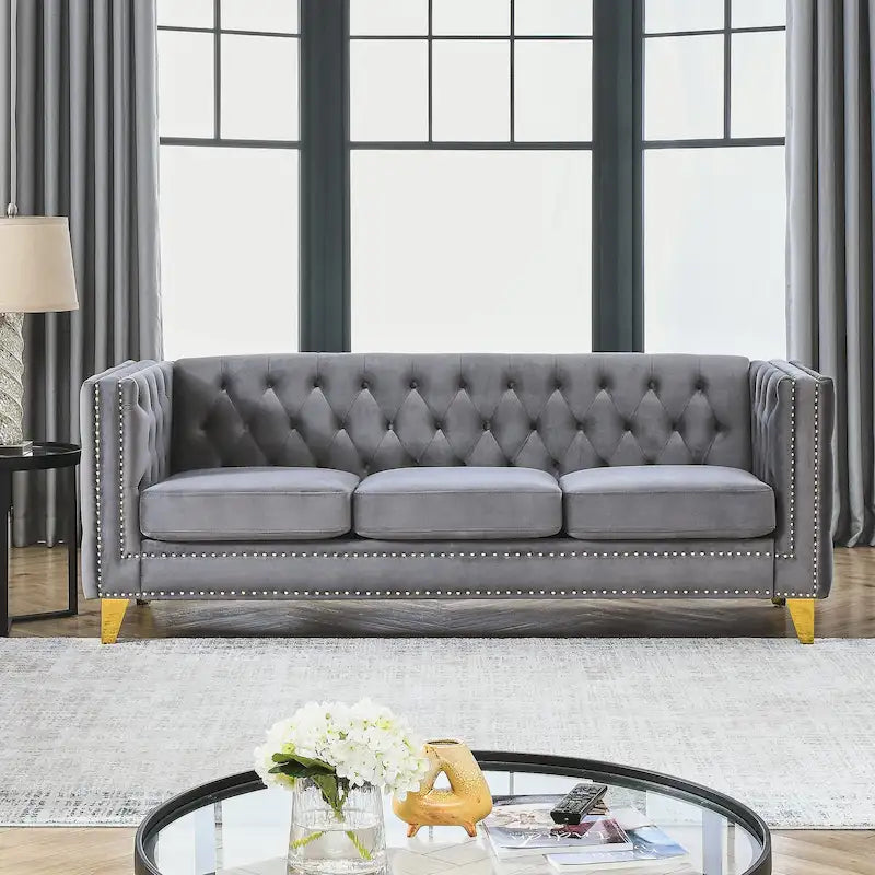 Sofá gris de terciopelo para tres personas, acolchado con botones decorativos, ribete de tachuelas y patas de metal