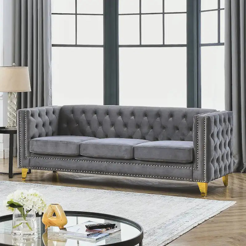 Sofá gris de terciopelo para tres personas, acolchado con botones decorativos, ribete de tachuelas y patas de metal