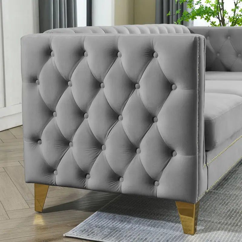 Sofá gris de terciopelo para tres personas, acolchado con botones decorativos, ribete de tachuelas y patas de metal