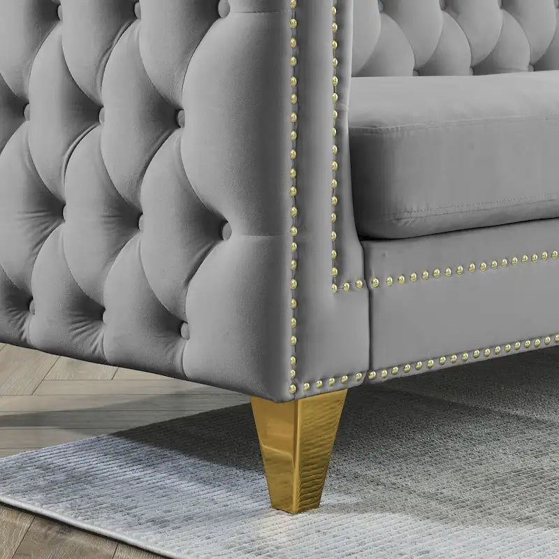 Sofá gris de terciopelo para tres personas, acolchado con botones decorativos, ribete de tachuelas y patas de metal