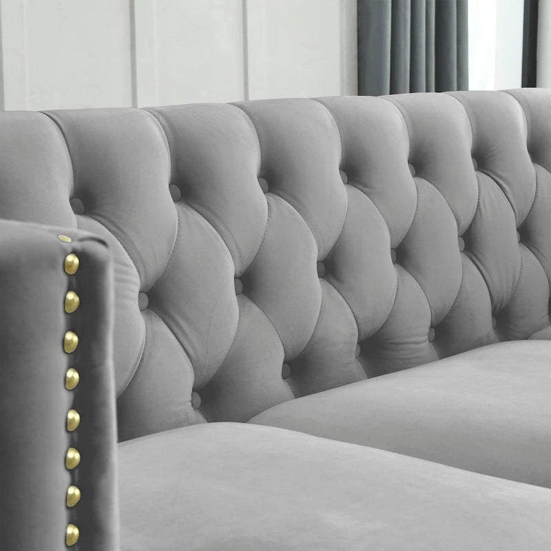 Sofá gris de terciopelo para tres personas, acolchado con botones decorativos, ribete de tachuelas y patas de metal
